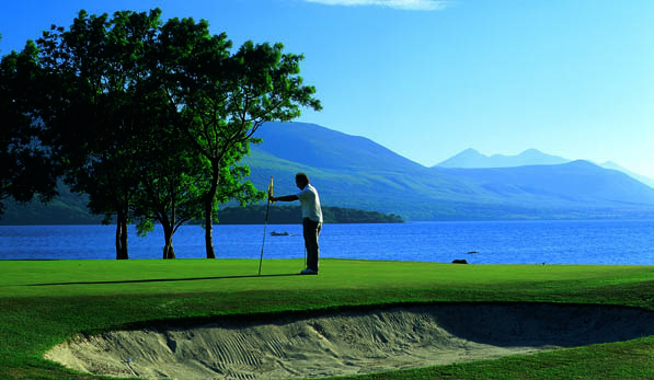 Man on a golf green holding the flag